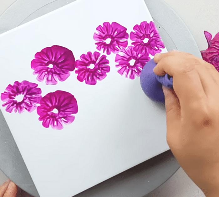 Balloon painting instructions showing the balloon pressed into paint to print flower petals on a canvas