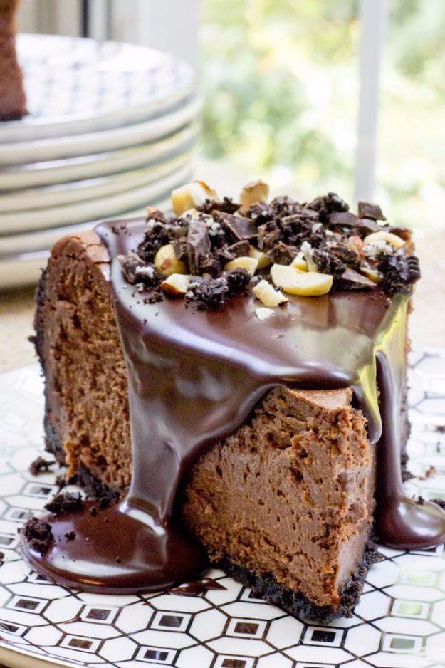 Chocolate hazelnut cheesecake with glossy ganache pouring down and chopped hazelnuts, on a geometric patterned plate