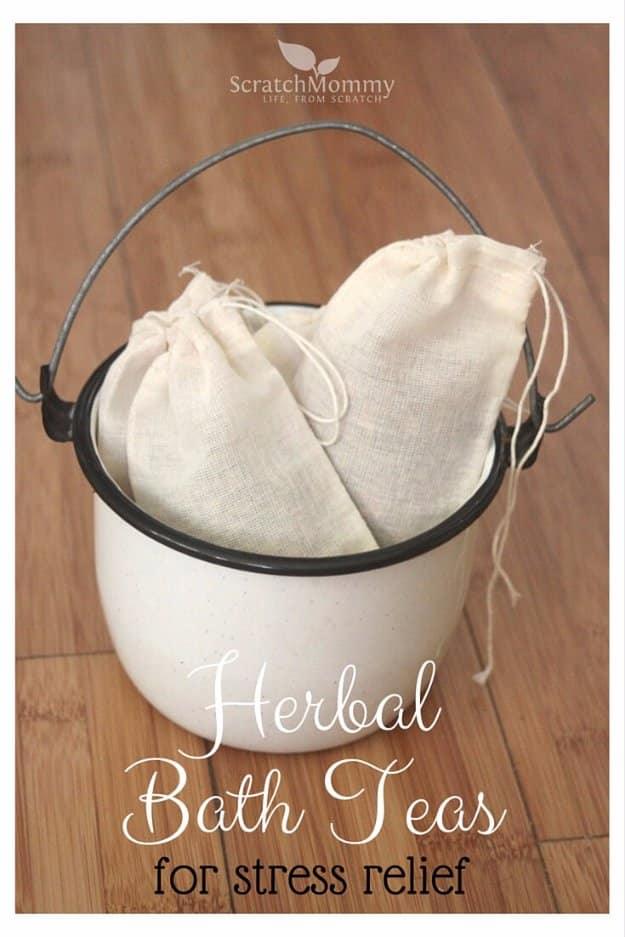 Muslin drawstring bags of herbal bath tea with kraft labels, spilling dried rose petals, oats and lavender on white marble