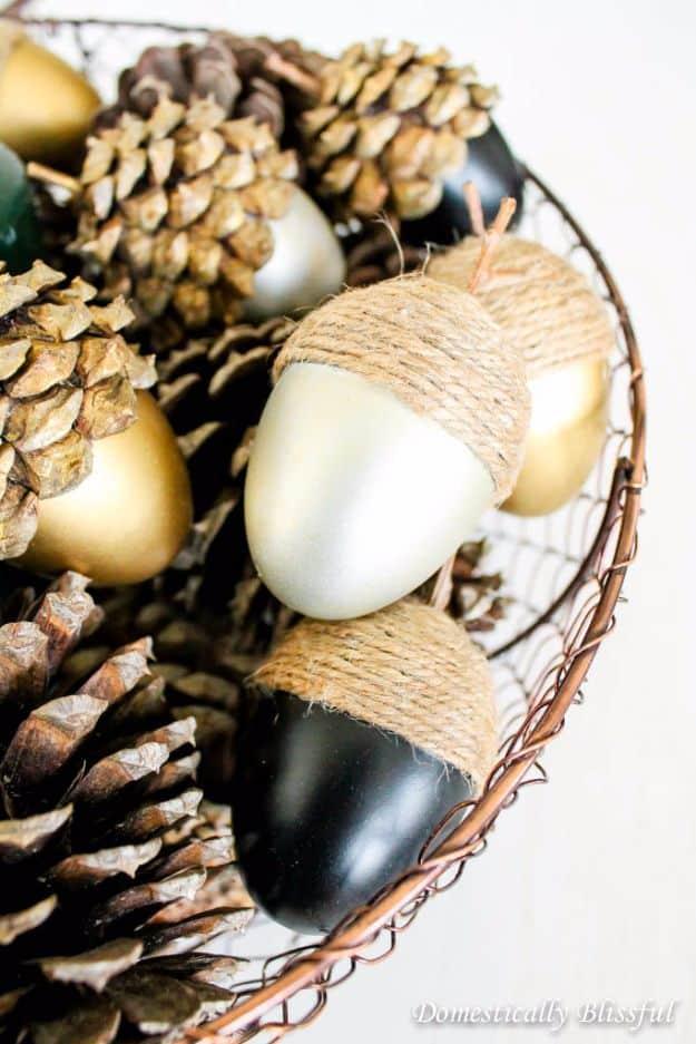 DIY fall acorns made from painted Easter eggs in gold, black and white with twine wrapped caps in a wire basket