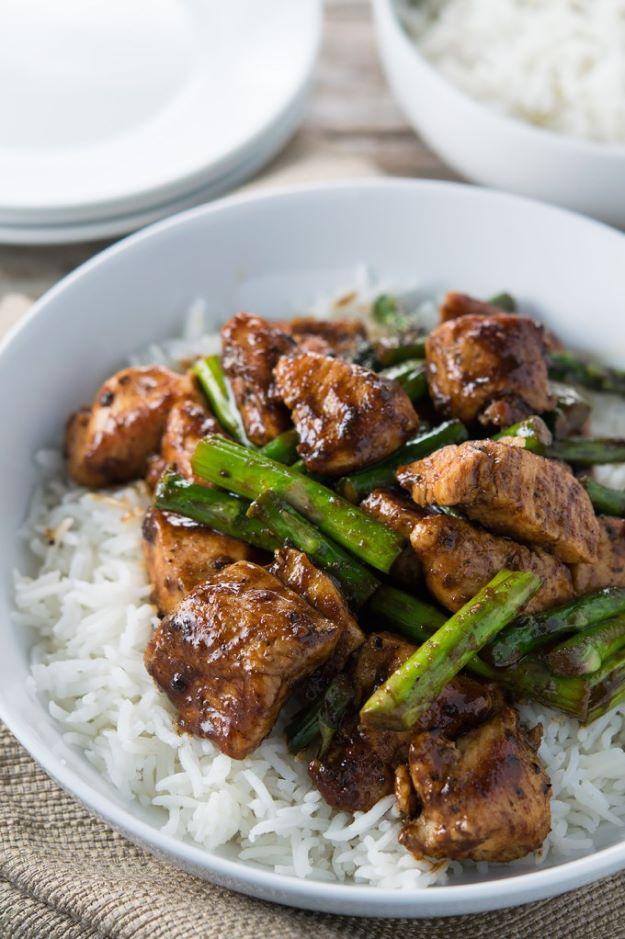 Black pepper chicken and asparagus stir fry in a bowl over white rice with glazed chicken and green spears