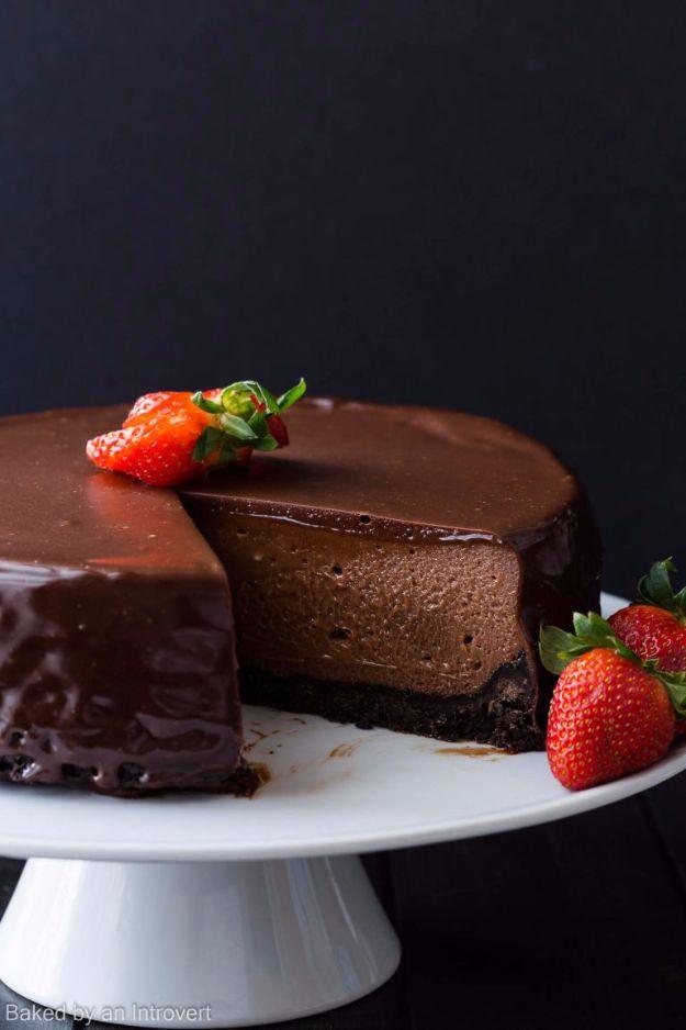 Nutella cheesecake with a glossy chocolate glaze poured over the top, sliced open beside fresh strawberries