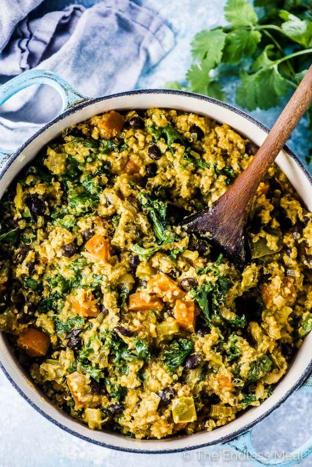 Curried quinoa vegetable stew with black beans and kale in a pot, thickened with peanut butter and cilantro