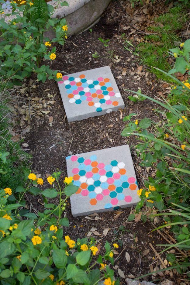 Two concrete stepping stones stenciled with colorful dots, set into a garden bed with yellow flowers