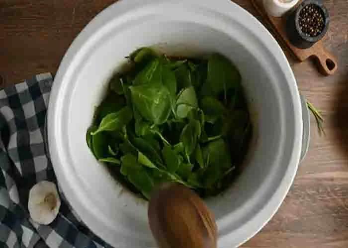 Adding the spinach to the slow cooker tuscan chicken