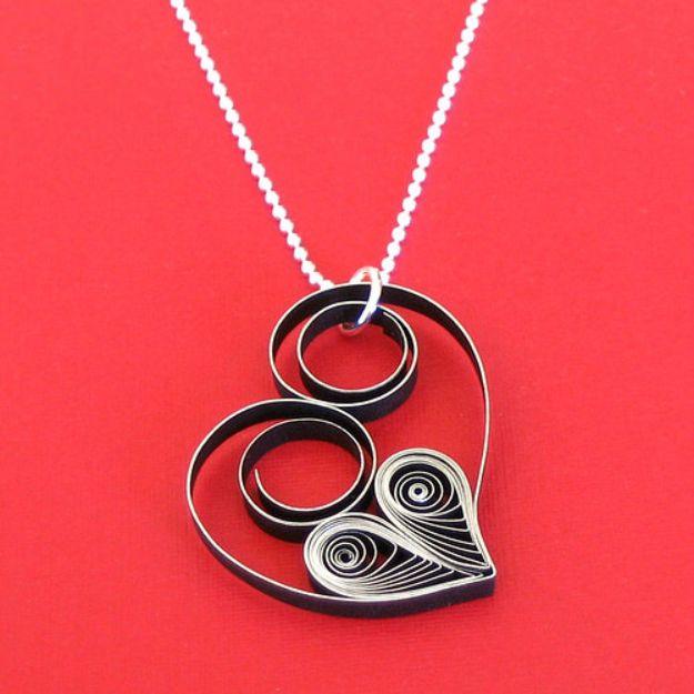 Quilled heart necklace, a black and silver quilled paper heart pendant on a fine chain against a bright red background