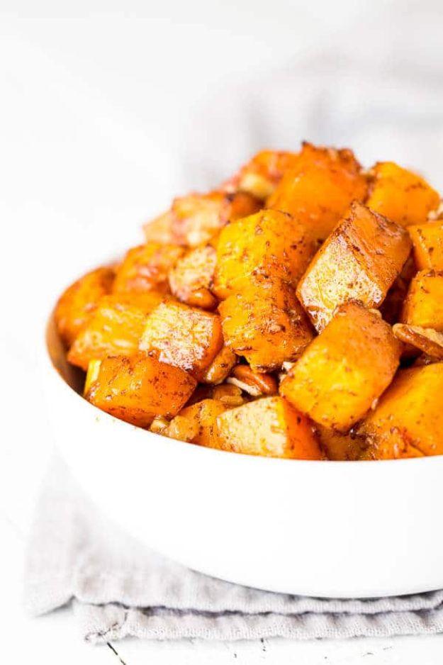 Caramelized butternut squash cubes in a white bowl with deep browned edges and toasted nuts mixed through