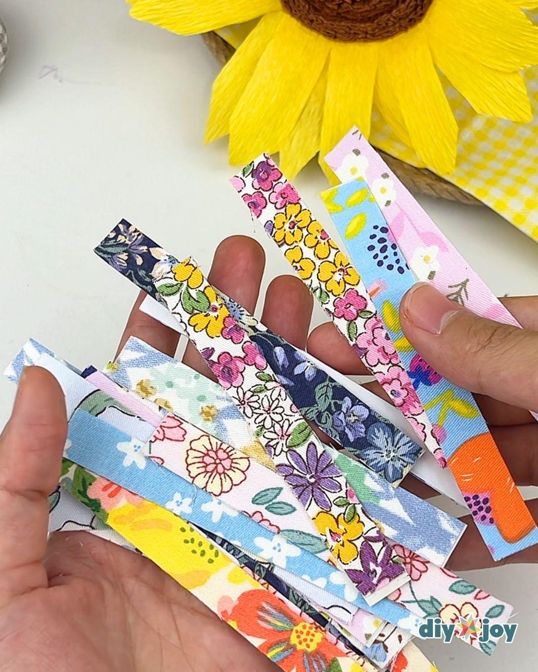 Fabric Tape DIY - a hand holding a fanned stack of bright blue, pink and yellow floral fabric tape strips