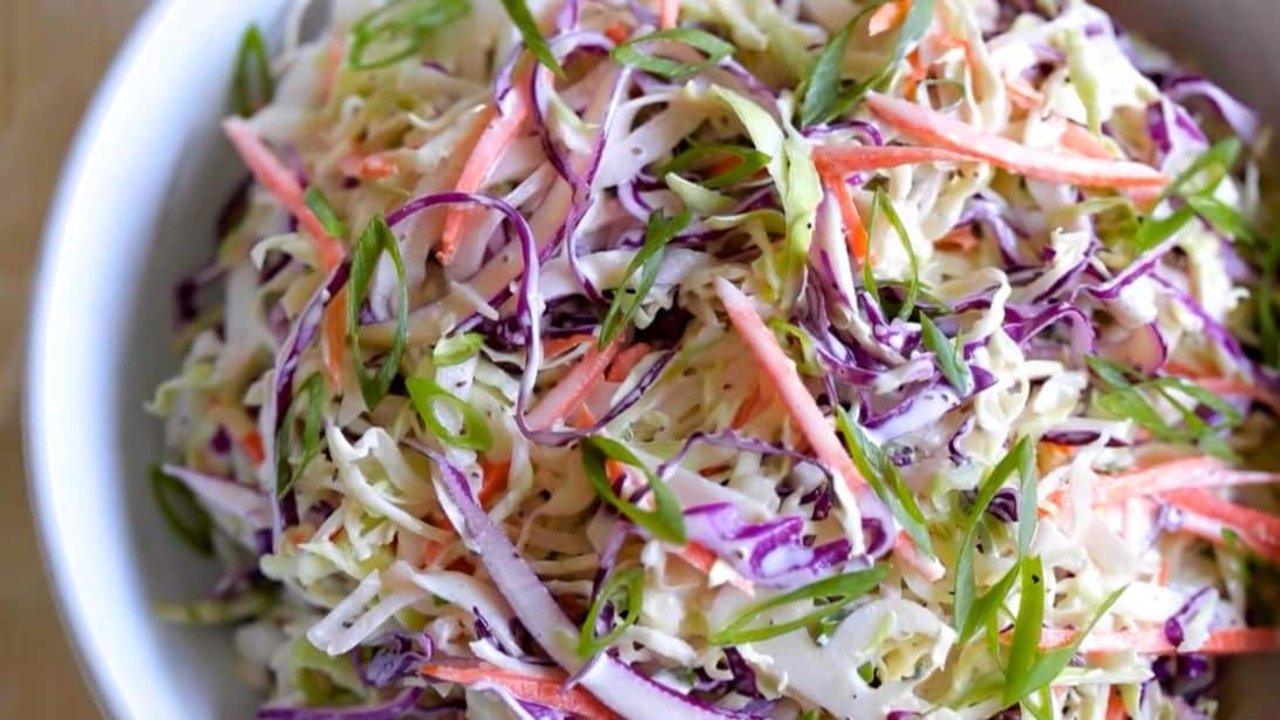 Memphis style creamy coleslaw with shredded green and red cabbage and julienned carrot in a bowl at a backyard cookout