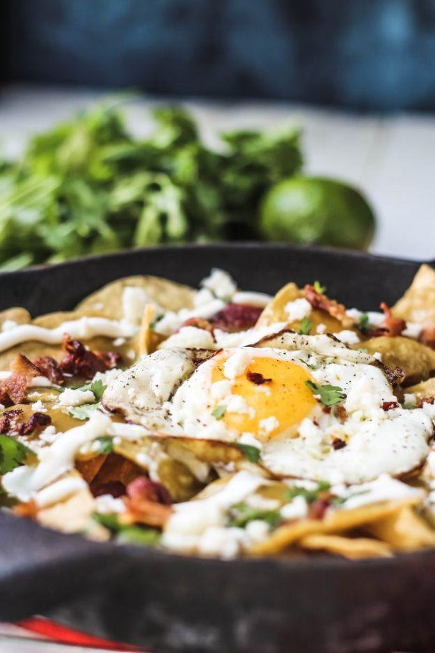 Bacon fried egg chilaquiles verdes in a cast iron skillet, tortilla chips in green sauce under a fried egg