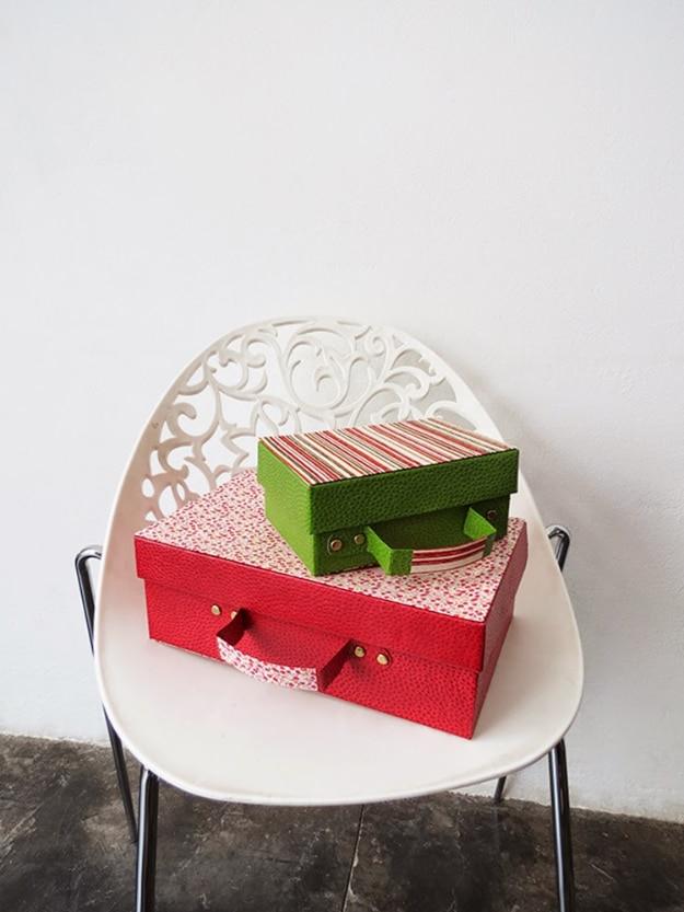 Recycled shoe box suitcase, two striped paper covered shoe boxes with ribbon handles stacked on a white chair