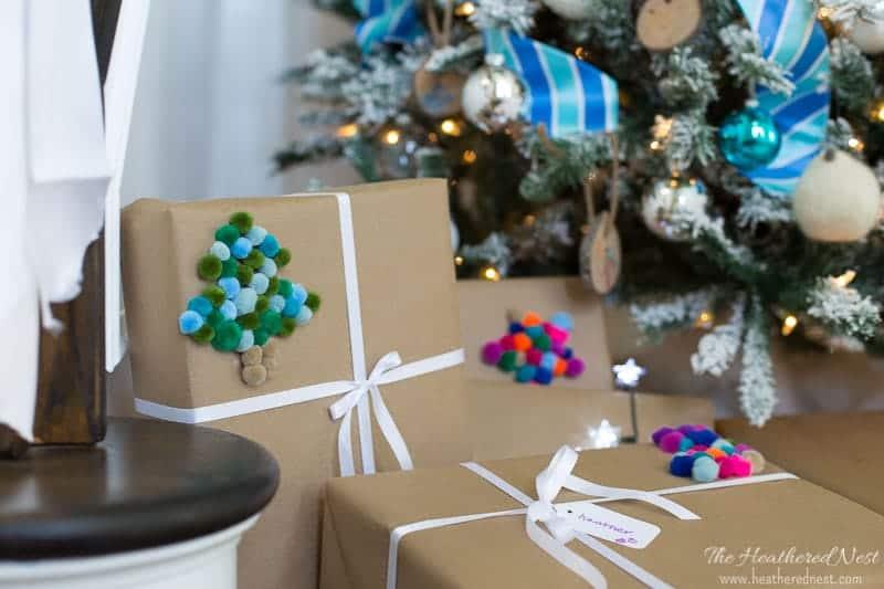 Kraft paper parcels decorated with pom pom Christmas trees in green and blue, tied with white ribbon