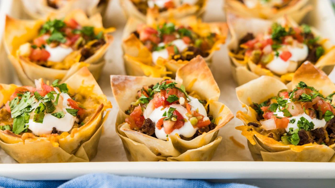 Taco cups baked in a muffin pan from wonton wrappers, filled with seasoned ground beef and cheddar cheese
