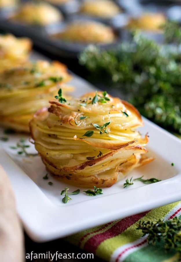White platter holding a tall stack of thin crisp layered potato slices topped with fresh thyme leaves