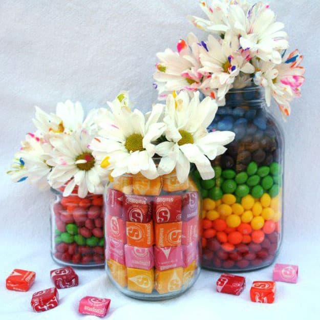 Mason jar packed with candy around a hidden cup of water holding fresh pink flowers for Valentine's to make at home