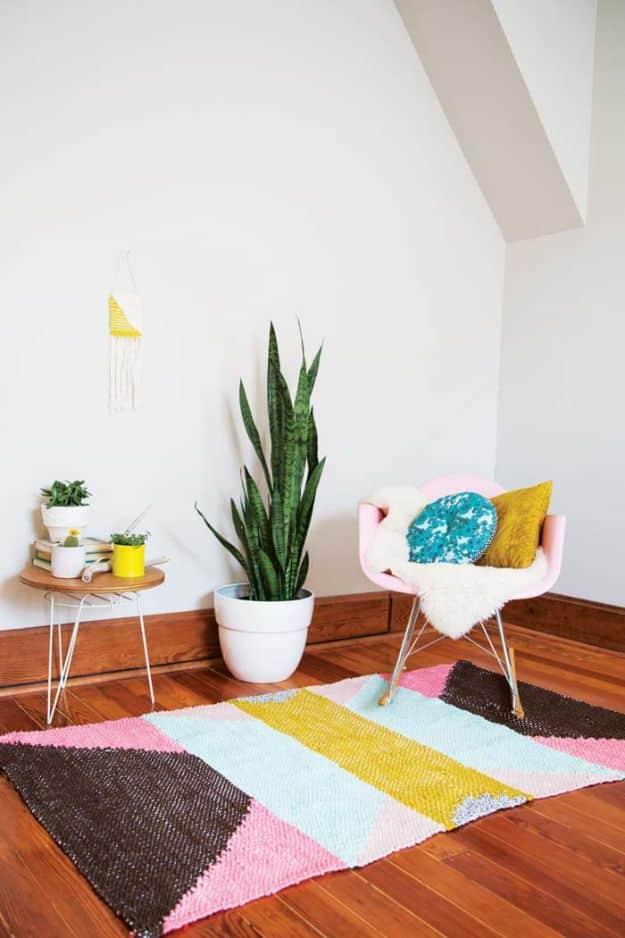 DIY rug in woven colour blocks of brown, pink, mint and mustard laid on bare wood boards in a bright attic room