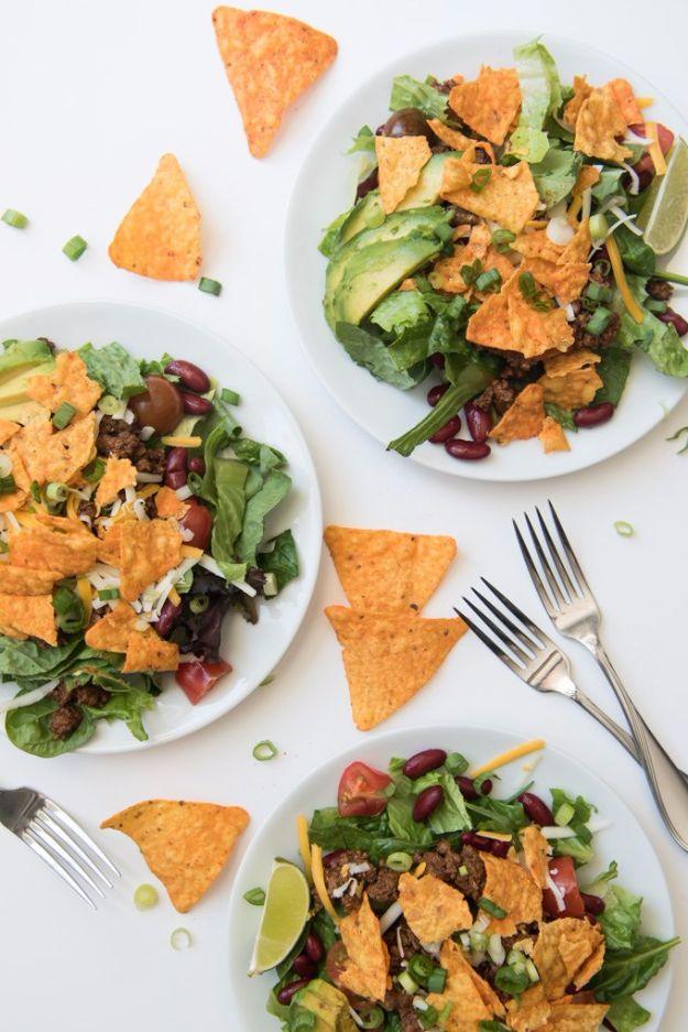 Tex Mex Doritos taco salad with ground beef, kidney beans, avocado and cheddar on three white plates