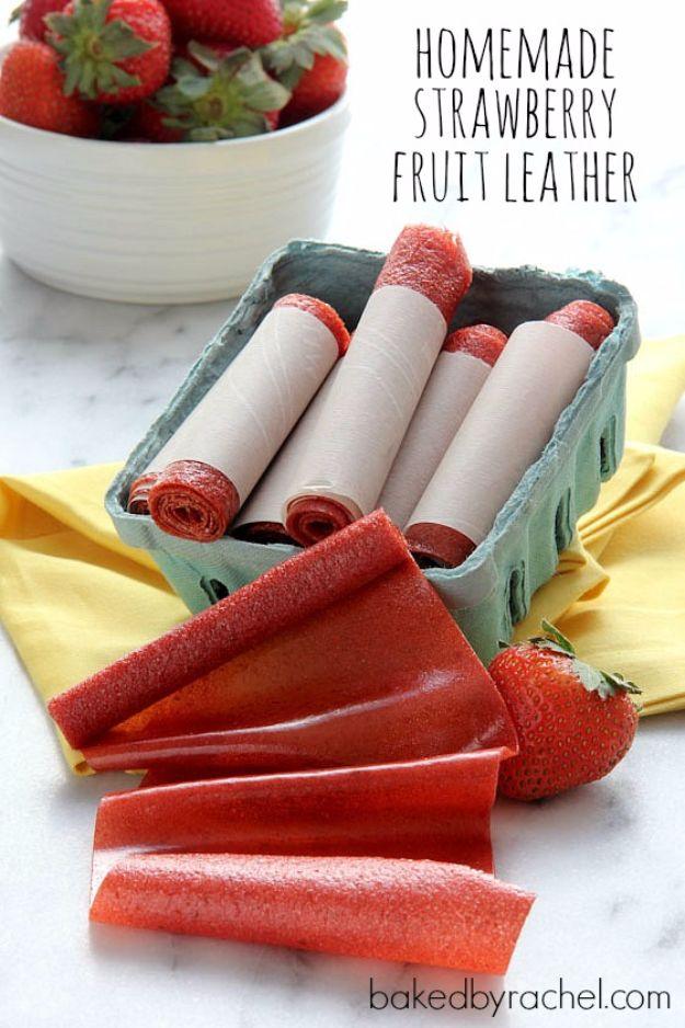 Homemade strawberry fruit leather rolled into red spirals in a berry basket beside fresh strawberries