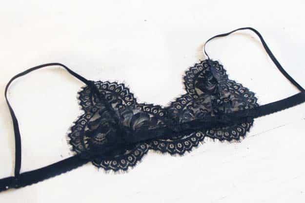DIY lace bralette, a black scalloped lace bralette with thin black elastic straps laid flat on a white surface