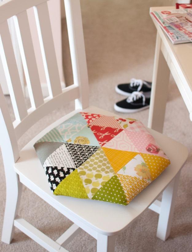 A retro patchwork seat cushion pieced from print triangles in red and mustard, tied onto a plain wooden kitchen chair.