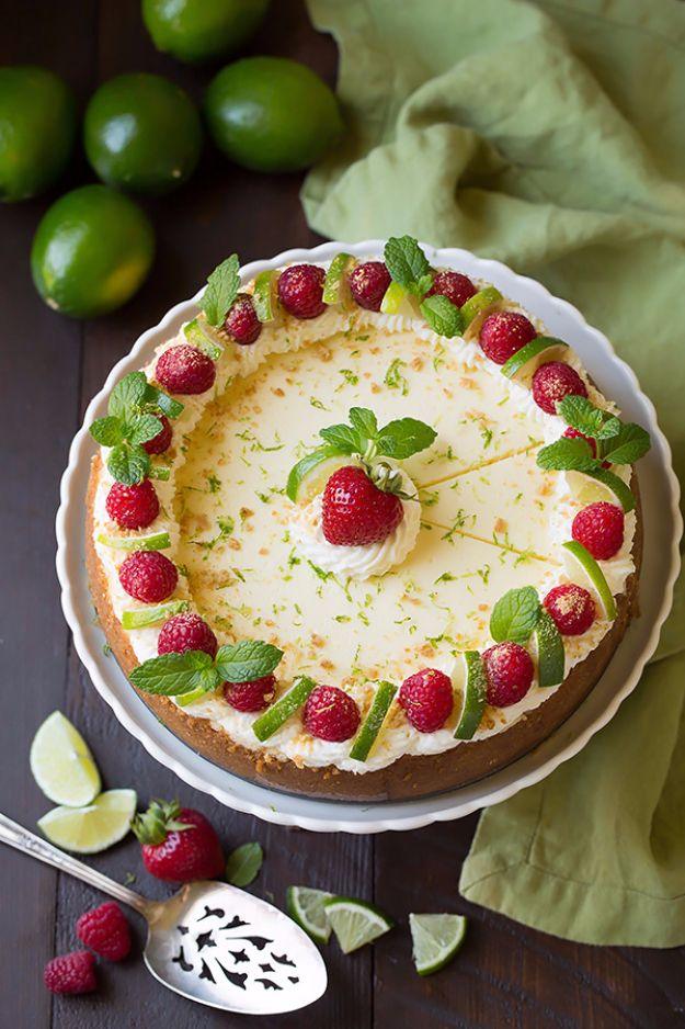 Key lime cheesecake topped with raspberries and lime slices on a graham crust beside fresh key limes