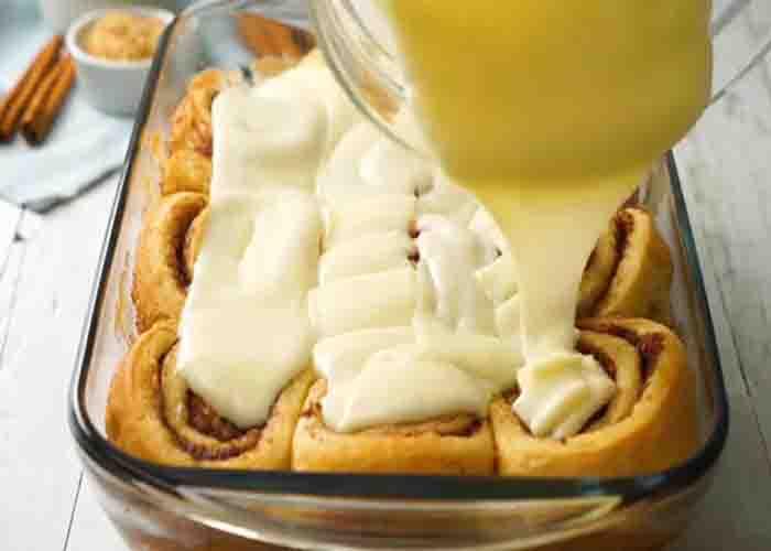 Spreading the icing over each cinnamon roll