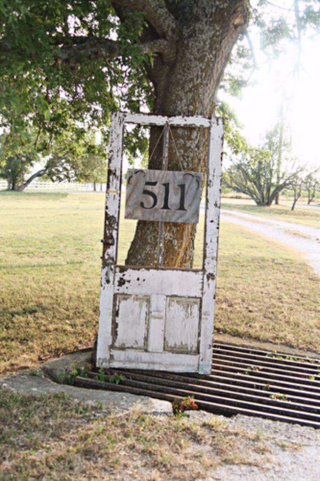 Old salvaged wooden door bolted to a tree with a hand painted house number sign reading 511 hung on it