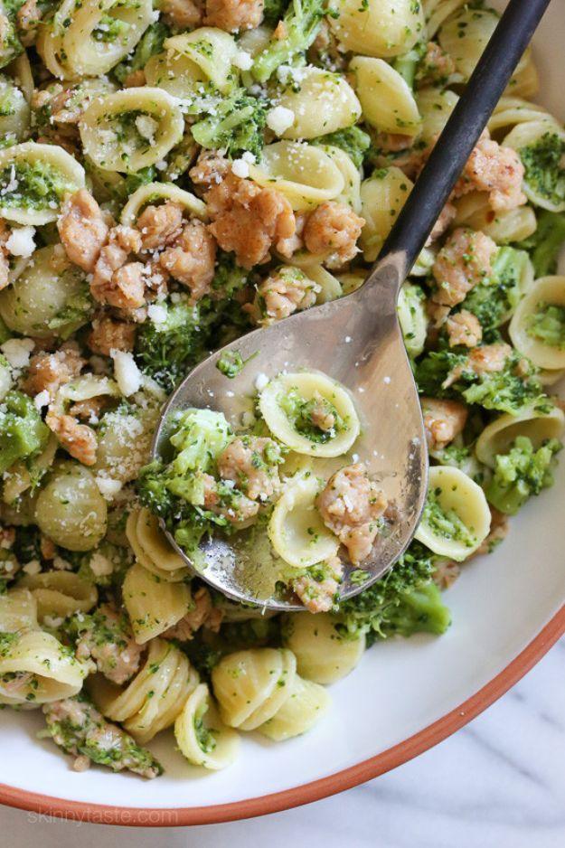Orecchiette pasta with chicken sausage and green broccoli florets in a white bowl with a metal serving spoon