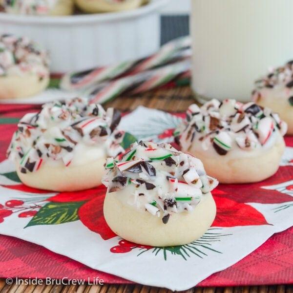 Snowball cookies dipped in white chocolate and topped with crushed candy canes and chocolate on a red poinsettia napkin