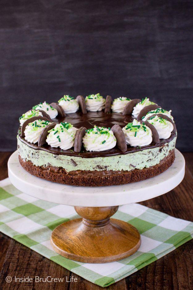 Thin mint cheesecake brownie cake on a wooden stand, mint green layer over brownie with cookie topped swirls