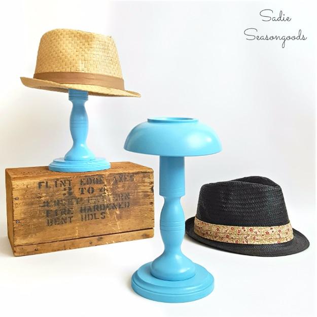DIY hat stands, upturned wooden bowls on turquoise candlesticks, one holding a straw trilby beside a wooden crate