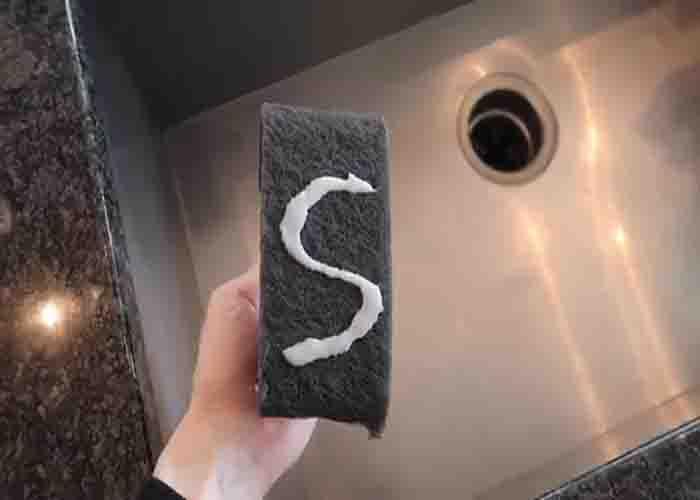 Adding the solution to the pad to remove scratches from stainless steel