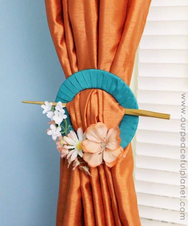 Curtain pull back made from an old CD wrapped in teal ribbon with silk flowers, holding an orange curtain