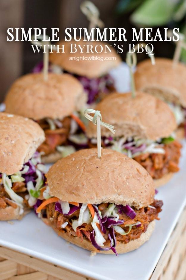 Instant Pot BBQ pulled pork shredded in sauce and piled onto slider buns with coleslaw on top on a cookout table