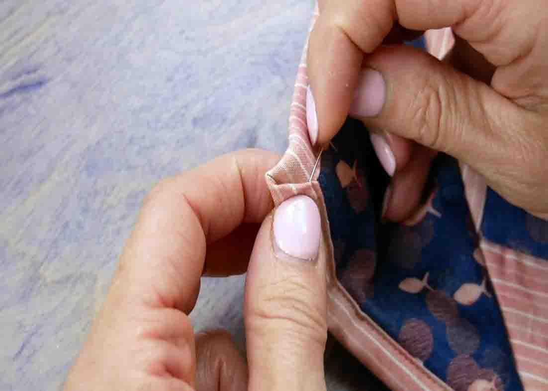 Hand stitching the mitered corners of the quilt