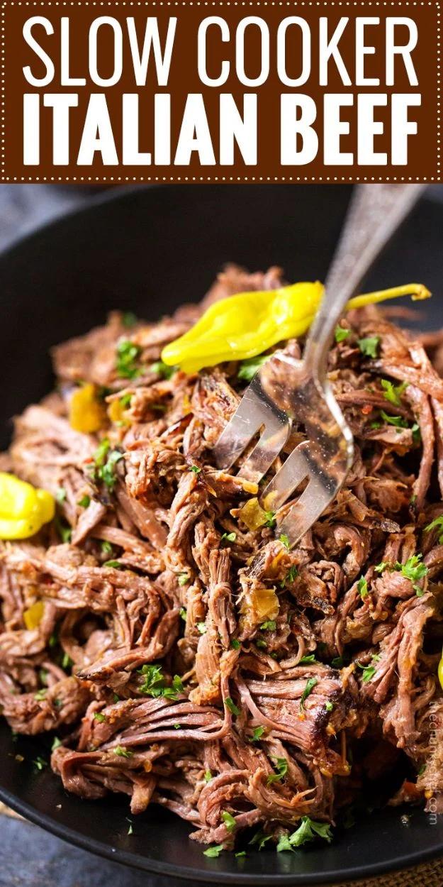 Slow cooker Italian beef shredded in its own juices with pepperoncini and banana pepper rings on a bun