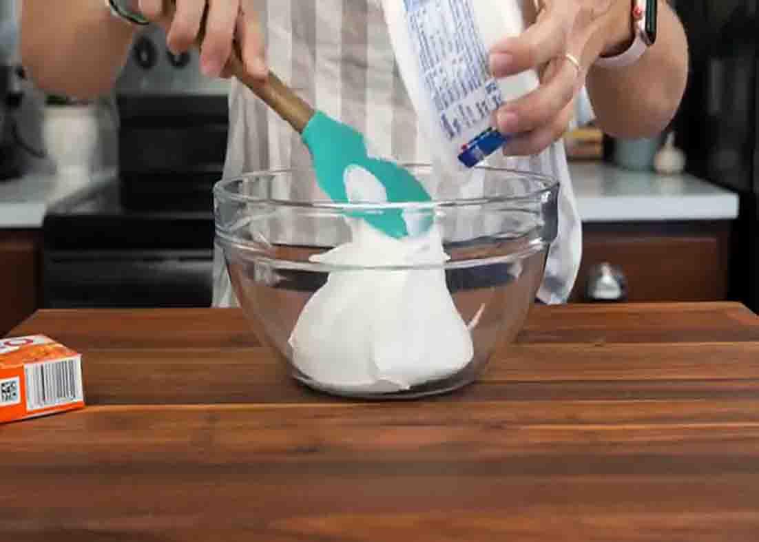 Adding the whipped cream on the bowl for the orange fluff salad