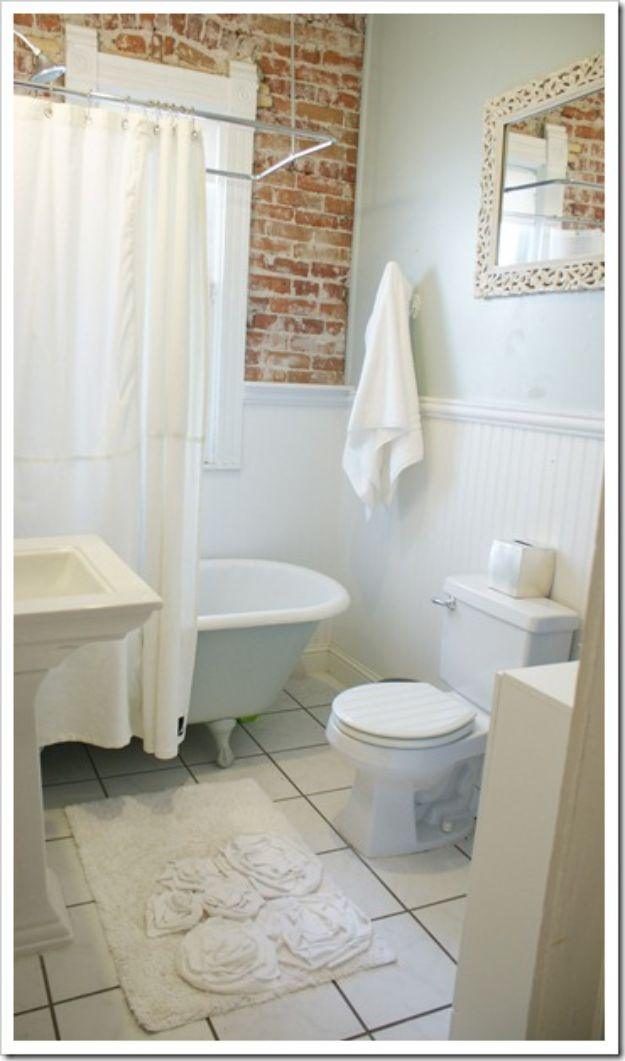 Cream bath mat DIY rug with white fabric roses grouped across one half, in a white bathroom with a claw foot tub