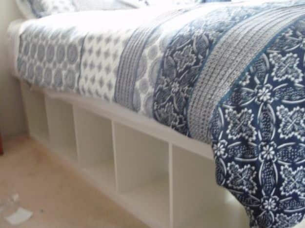 IKEA Expedit shelving unit repurposed as a bed frame with open storage cubes under a quilted mattress