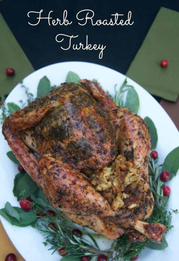 Herb roasted turkey with whole sage leaves visible under the golden skin, resting in a large roasting pan