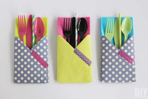Three folded paper cutlery holders in gray polka dot and lime paper, each holding colored plastic forks, knives and straws