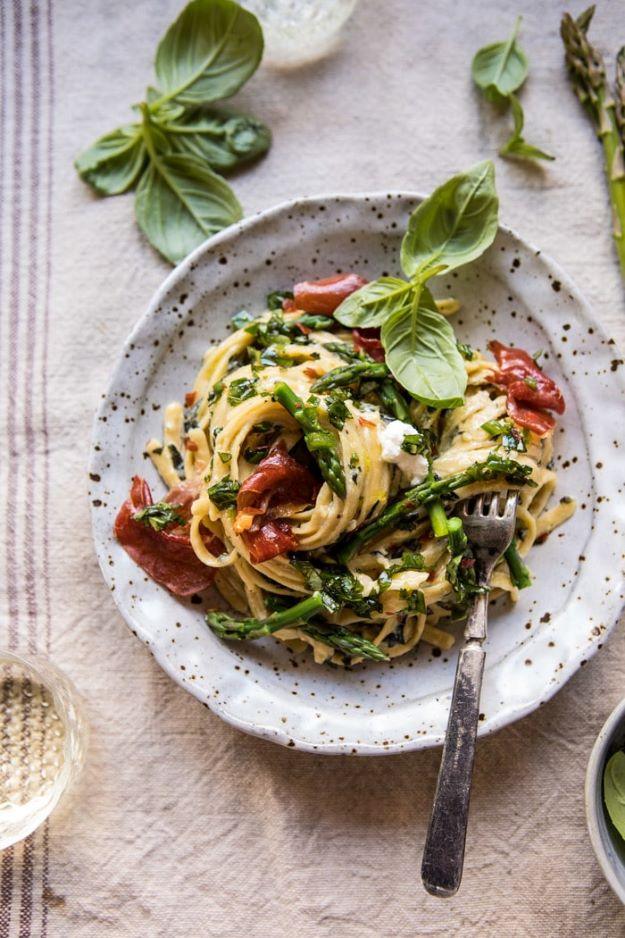 Spicy pesto asparagus and ricotta pasta on a speckled plate with green pasta, tomatoes and fresh basil
