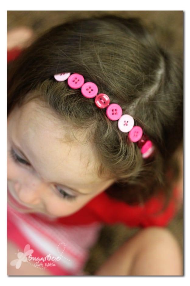 Button headband, a row of small pink and white buttons sewn along a flat elastic headband worn over dark hair