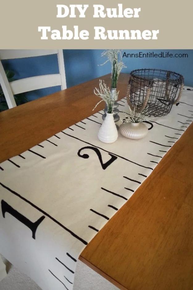 Cream table runner painted with black ruler markings and numbers, running across a wooden dining table with vases