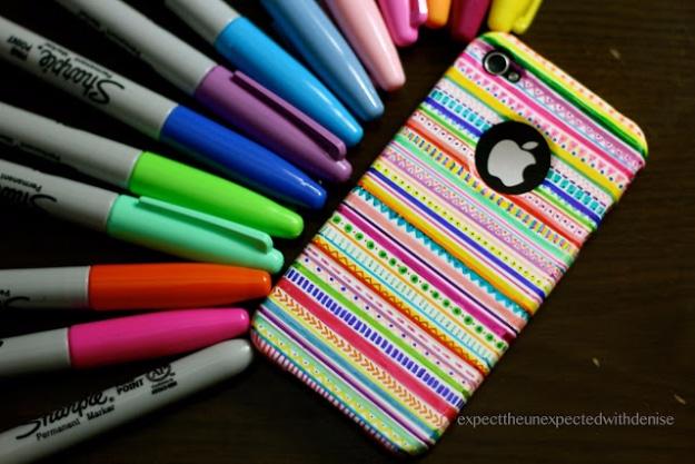 DIY tribal print iphone case, a white phone case drawn in rainbow striped pattern bands beside a fan of Sharpies