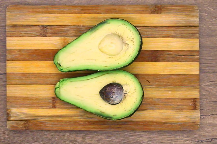 Fresh avocado halved on a wooden cutting board to make avocado chips