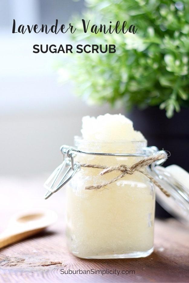 Lavender vanilla sugar scrub in a clamp lid jar tied with twine, a wooden spoon and a leafy plant behind