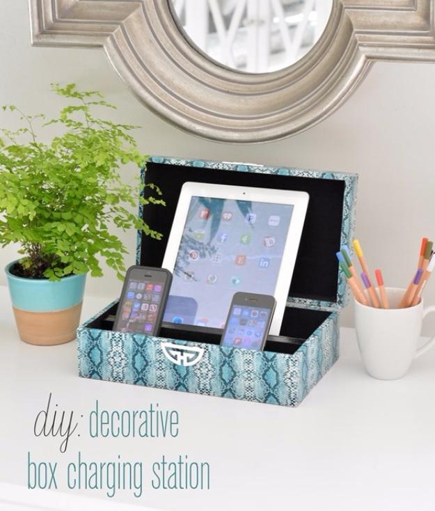 Decorative box charging station, a patterned box holding a tablet and two phones charging beneath a round mirror