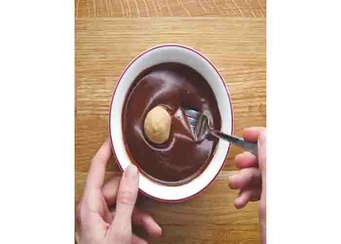Coating the peanut butter balls with chocolate ganache