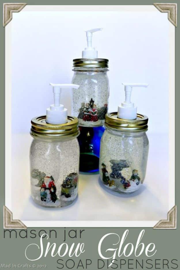 Three mason jar snow globe soap dispensers with Christmas village figures glued inside and glitter floating in clear soap